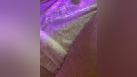 Video of a close-up, blurred view of a person's upper thigh and inner thigh, with a white towel partially covering the skin. The skin is slightly tanned, and the towel has a soft texture.