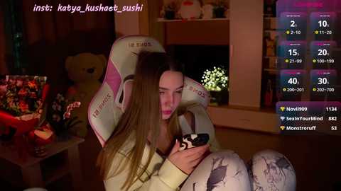 Media: Video of two young women cuddling in a cozy room with a fireplace and plush toys. One woman has a white bear head pillow.