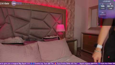 Media: Video of a modern bedroom with a grey upholstered headboard, two pillows, a nightstand, and a red accent light.