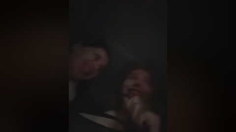 Media: Blurry video of a man and woman in a dimly lit room, possibly in a nightclub, with dark, moody lighting. The woman is touching her face and appears distressed.