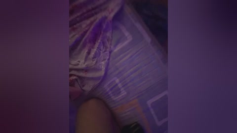 A dimly lit video showing a person in a white t-shirt with red stains, possibly blood, and a purple shirt, suggesting a distressed or injured state. The background is dark and indistinct.