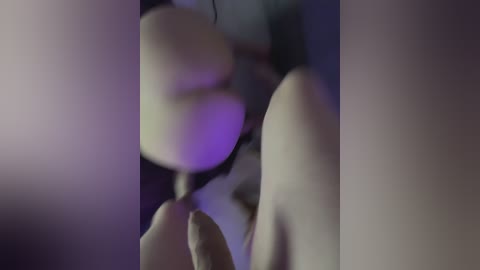 Blurry video of a person in a dark room, with a purple light source creating a soft, indistinct silhouette.