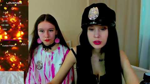 Media: Video of two young women, one in a tie-dye top, the other in a police cap, in a cozy indoor setting with Christmas lights.