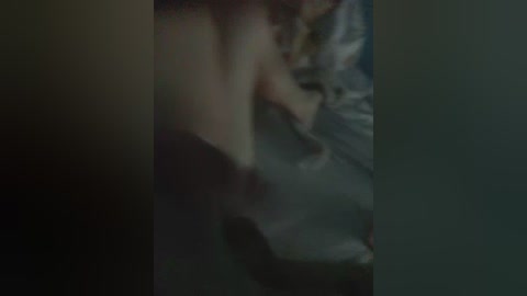 Blurry, low-light video of a person lying on a bed, partially obscured by shadows and indistinct objects, with a dark, unidentifiable object in the foreground.