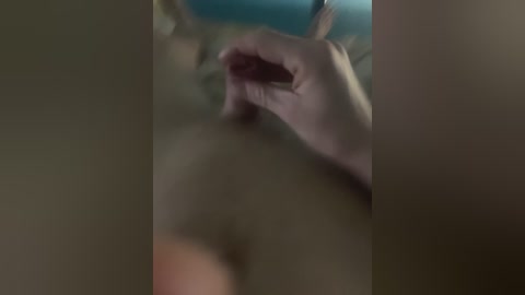 Video of a close-up, blurred scene featuring a hand holding a smartphone, possibly taking a selfie. Background indistinct, likely a dimly lit room. The image appears grainy and out of focus.