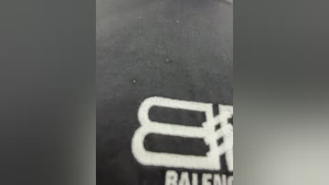 Media: A close-up video of a black plastic water bottle with white text and symbols, including a stylized \"R\" and \"B\" logo, likely from a sports brand. The surface is slightly textured and the bottle appears clean.