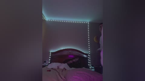 Media: A dimly-lit video of a bedroom with a wooden bed, a purple duvet, and blue LED strip lights on the ceiling and walls, creating a cozy, intimate atmosphere.