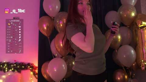A video of a young woman with long red hair, wearing a gray shirt, holding a phone, surrounded by golden balloons, with a festive, dimly lit background and social media icons in the corner.
