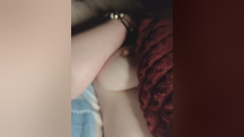A close-up video of a woman's hand with a delicate gold bracelet, resting on a red lace dress. The background is blurred, focusing attention on the intricate details of the bracelet and fabric.