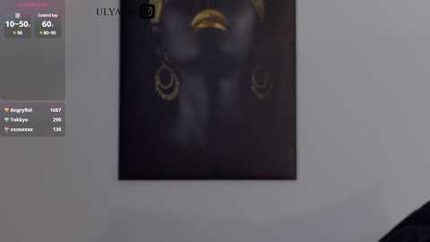 A video showing a close-up of a black and white image of a person wearing a dark outfit with a golden necklace and earring. The background is a plain white wall.
