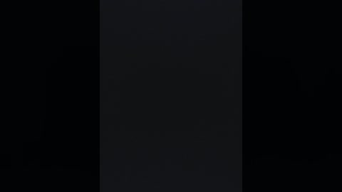 A black-and-white video of a vertical, narrow, dark band against a black background, creating a stark contrast. The image is minimalistic, with no discernible objects or details.