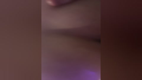 A blurred, close-up video of a person's face with a soft, pinkish hue. The image is out of focus, making it difficult to discern specific features.