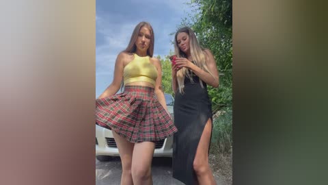 Media: Video of two young women, one in a yellow crop top and red plaid skirt, the other in a black dress with a high slit, posing outdoors near a car.