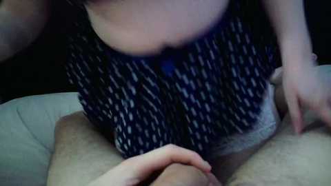 A video shows a woman with fair skin and a dark, patterned top, sitting on a man's lap, his erect penis visible.