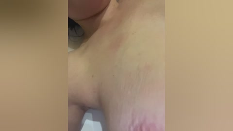 Close-up video of a person's bare back, showing skin texture, slight redness, and a small tattoo.
