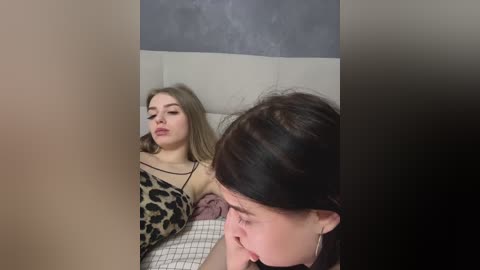 Media: Video of a young woman with light skin, long brown hair, and a leopard-print top lying on a bed, while a young girl with dark hair is seen kissing her cheek.