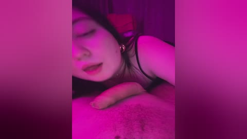 A video with a pinkish-purple tint shows a young woman with long hair and fair skin, partially obscured by a man's erect penis. She wears a black top and is lying on her side.