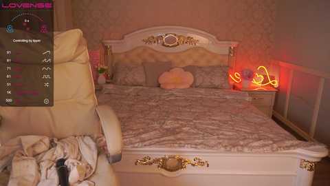 Video of a luxurious, ornate bedroom with a plush cream-colored leather chair, a romantic gold-framed bed adorned with patterned bedding, a cozy red neon heart lamp, and a soft, floral wallpaper.