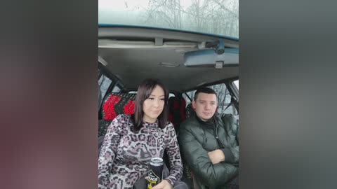 Media: Video of a woman with straight brown hair, wearing a leopard-print sweater, and a man with short hair, in a car, both sitting in the backseat, looking serious.
