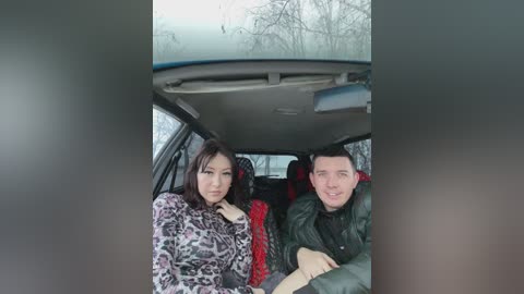 Media: Video of a woman with long dark hair in a leopard print sweater and a man in a green jacket, seated in a car with frosty windows, during a snowy day.
