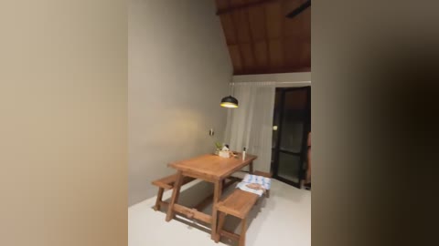 Media: Video of a minimalist, cozy dining room with wooden table, benches, hanging lamp, and white curtains.