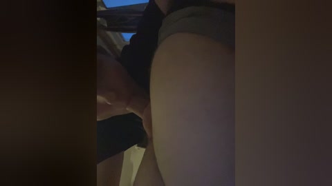 A dimly lit video captures a close-up of a woman's vagina being licked by a man's tongue, with her thighs slightly parted. The background is dark and indistinct.