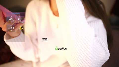 Media: Video of a woman with long brown hair, wearing a white ribbed sweater, holding a pink vibrator. The image includes a digital thermometer display showing temperature and time.