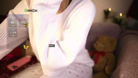 Media: Video of a woman in a white sweater, holding a teddy bear, with a digital overlay showing temperature and humidity readings.