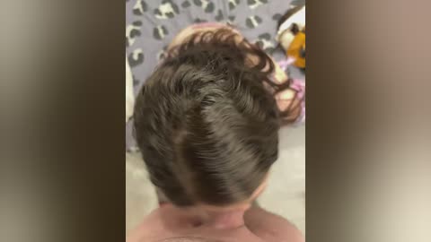 Media: Video of a man with short, neatly styled dark brown hair, viewed from behind. He is shirtless, with his head turned slightly to the right. Background shows a tiled wall with a leopard print pattern.