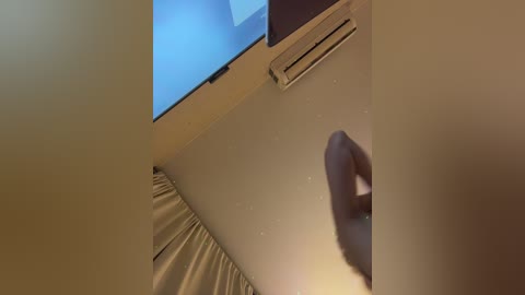 Video of a beige wall with a hand reaching out, a vent, and a window with a blue curtain.