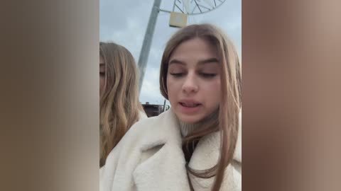 Media: A video of a young woman with long, straight blonde hair, wearing a white, fluffy bathrobe, captured in a mirror reflection. The background shows a large clock.