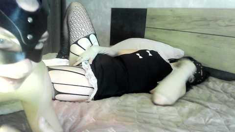 Media: Video of a woman in a black dress and white stockings lying on a bed with a dog resting beside her.