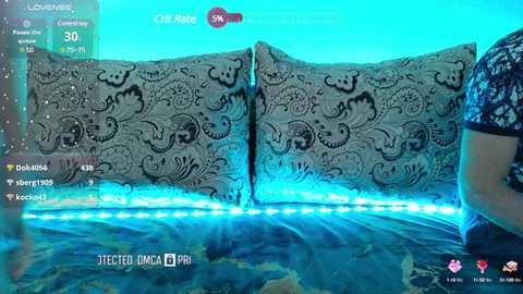 Media: A video of a person wearing a blue patterned shirt, sitting on a blue couch with ornate black patterns, under a blue-lit room.