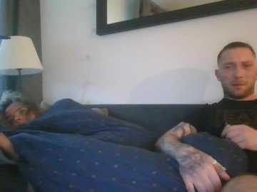 Video of a woman in dark pajamas, asleep on a bed, next to a man in a black shirt, both in a dimly lit room.