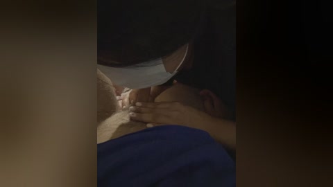 A video depicts a dark-haired man in a surgical mask performing oral sex on a person with a visible penis, wearing a blue shirt.