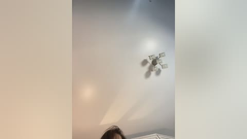 Media: A video of a beige ceiling with a white ceiling fan and a small portion of a person's head and neck visible at the bottom.