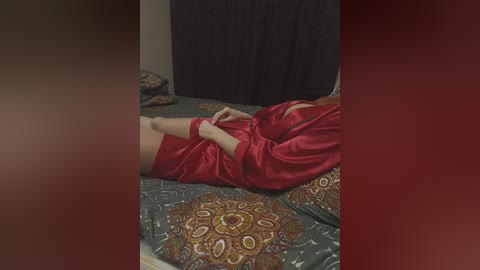 Media: A video of a person in red satin pajamas lying on a patterned bedspread, partially obscured by a dark curtain. The room has a dim, intimate atmosphere.