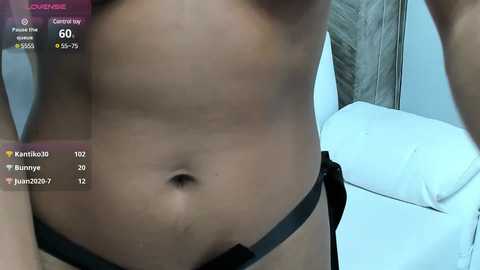 Video of a fit, light-skinned man's torso, wearing black underwear, with a white leather couch in the background.
