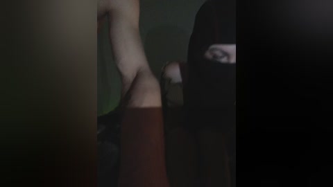 Video of a man's naked torso, with a blurred face, and a black mask covering his eyes. He is wearing a brown shirt, with a dark background.