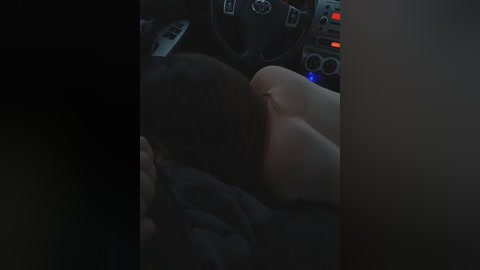 Video of a dimly-lit car interior with a woman's head resting on a man's shoulder, visible in the background.