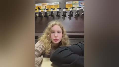 Media: A video shows a young woman with curly blonde hair, wearing a striped sweater, seated at a table in a fast-food restaurant. Behind her, a row of black and white figurines and a menu board are visible.