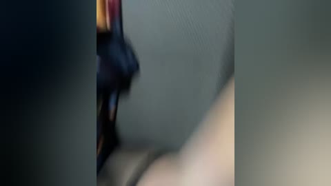 A close-up, blurred video of a person's face, with a dark-skinned person in the background. The focus is on the person's mouth, revealing a hint of teeth and lips.