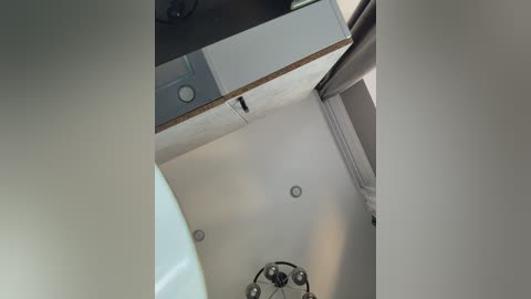 Video of a modern ceiling with recessed lighting, a white wooden panel, and a metallic ceiling fan, taken from a low angle.