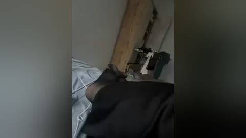 A video shows a person in a black shirt lying on a bed with a light blue blanket, next to a wooden door and a small desk with a lamp.