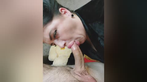 A video shows a close-up of a light-skinned woman with black hair, wearing a black top, performing oral sex on a light-skinned man with a circumcised penis.