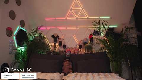 Video of a cozy living room with a plush brown couch, green plants, and a glowing, geometrically-patterned light display on the wall.