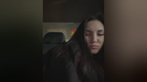 A video of a young woman with long, dark hair, wearing a black robe, looking sad and slightly out of focus, in a dimly lit room.