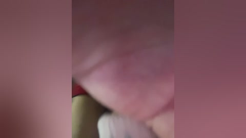 A blurred, close-up video of a person's face and mouth, with a red and white object visible. The background is pink.