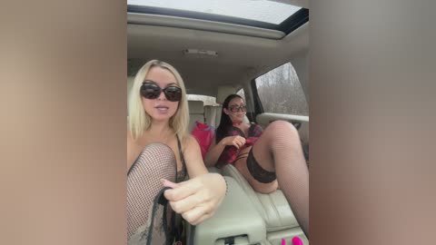 A video of two women in a car, one with blonde hair, wearing black fishnet stockings, and the other with dark hair, both in lingerie.
