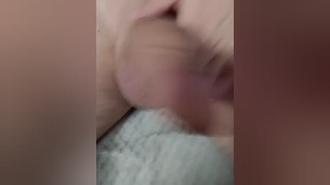 Blurry video of a close-up, intimate scene featuring a penis and testicles, with a light skin tone and a textured background.